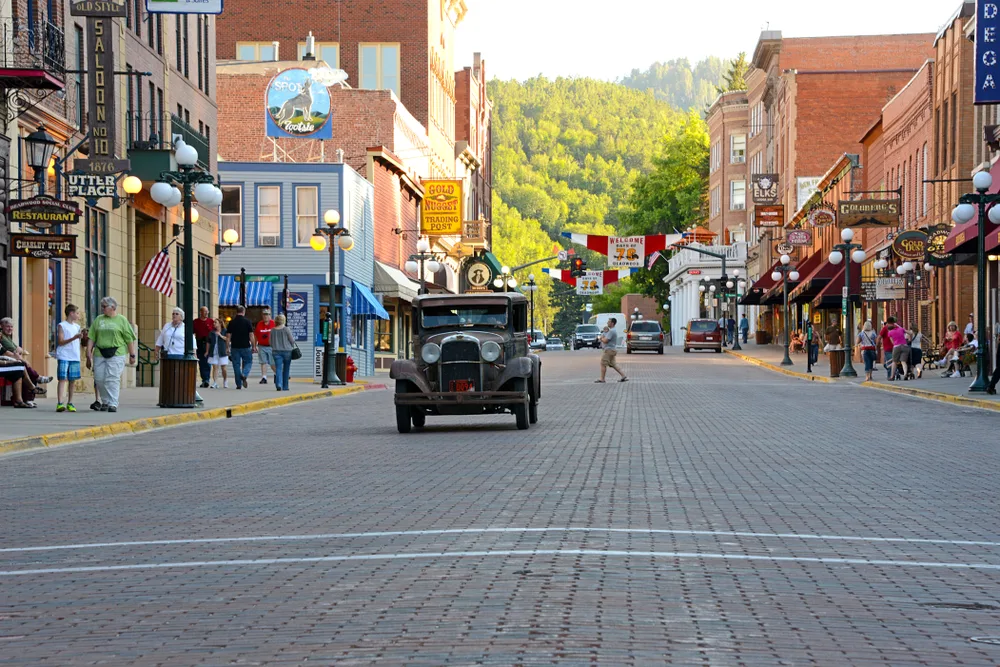 Old-time car driving down the street of one of the best places to visit in South Dakota, Deadwood