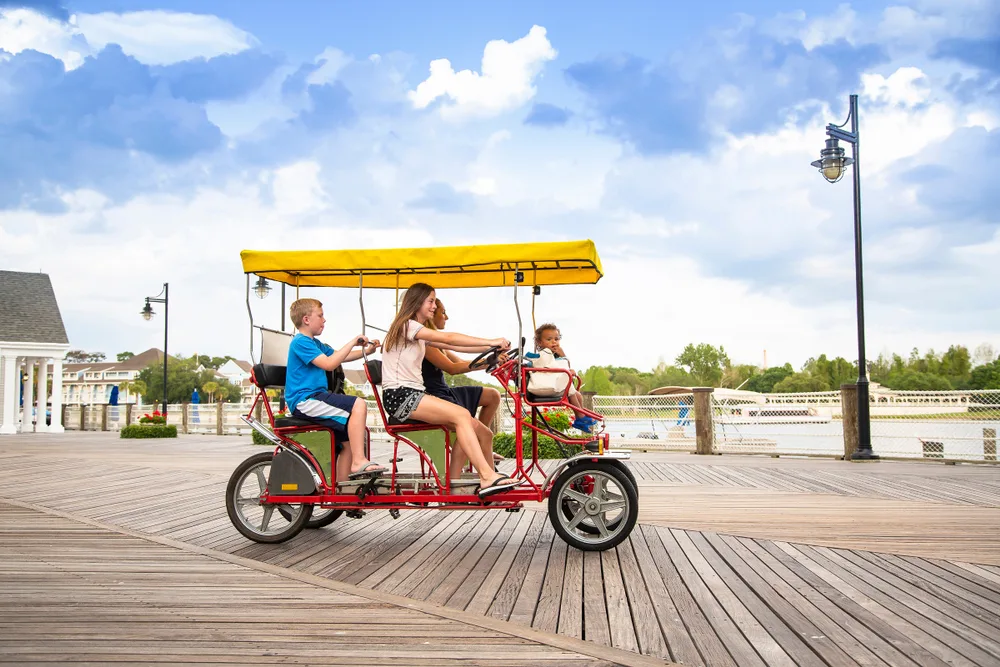 Family riding a four-seat bicycle on a boardwalk in Orlando, one of the best family vacation spots in the USA