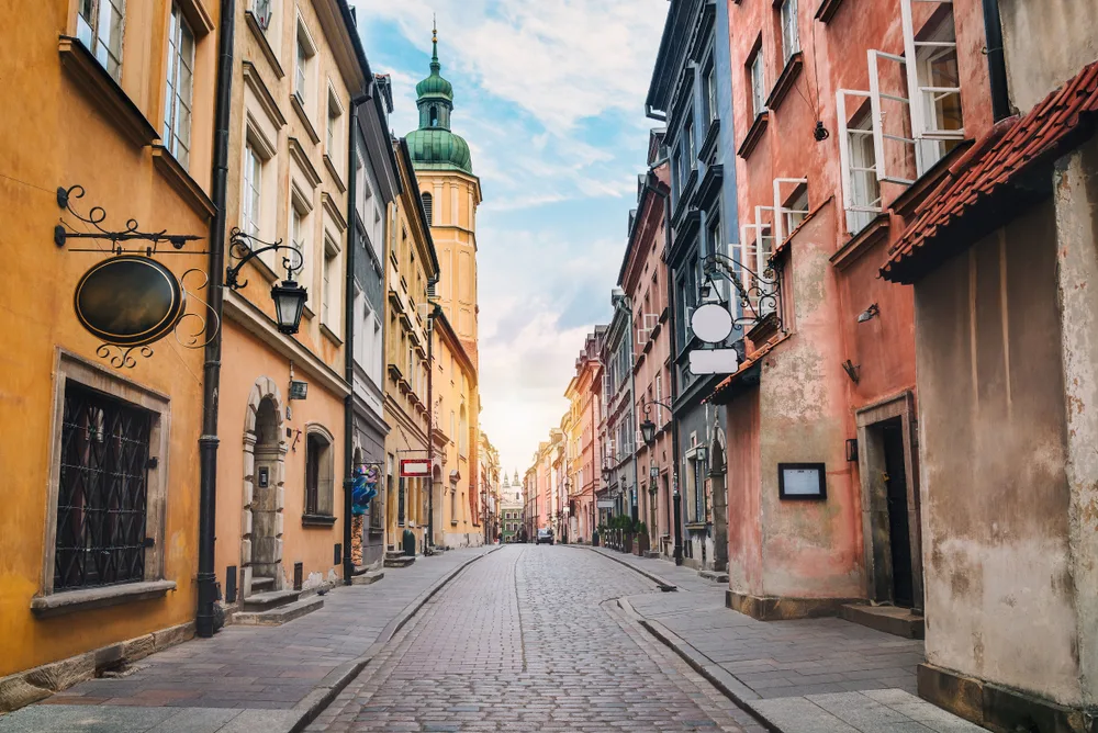 City street with cobblestones in the middle of large and historic buildings in Warsaw, a top pick for the best places to visit in Poland