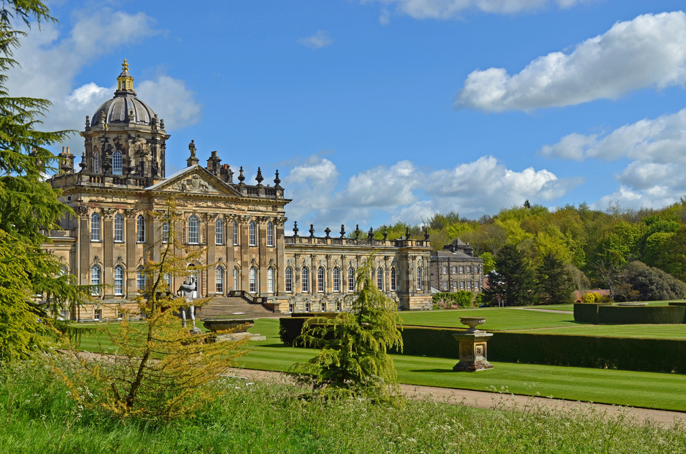 Artistic view of the Castle Howard, one of the best places to visit in England, as seen on a clear spring day with its stunning gardens in full view of the reader