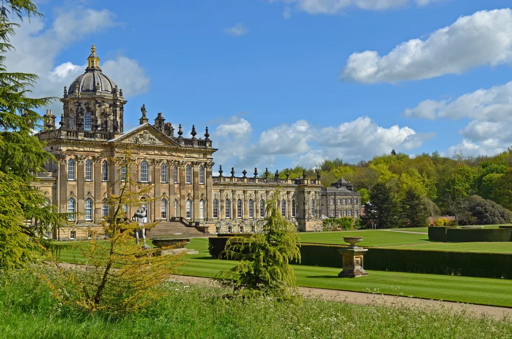 Artistic view of the Castle Howard, one of the best places to visit in England, as seen on a clear spring day with its stunning gardens in full view of the reader