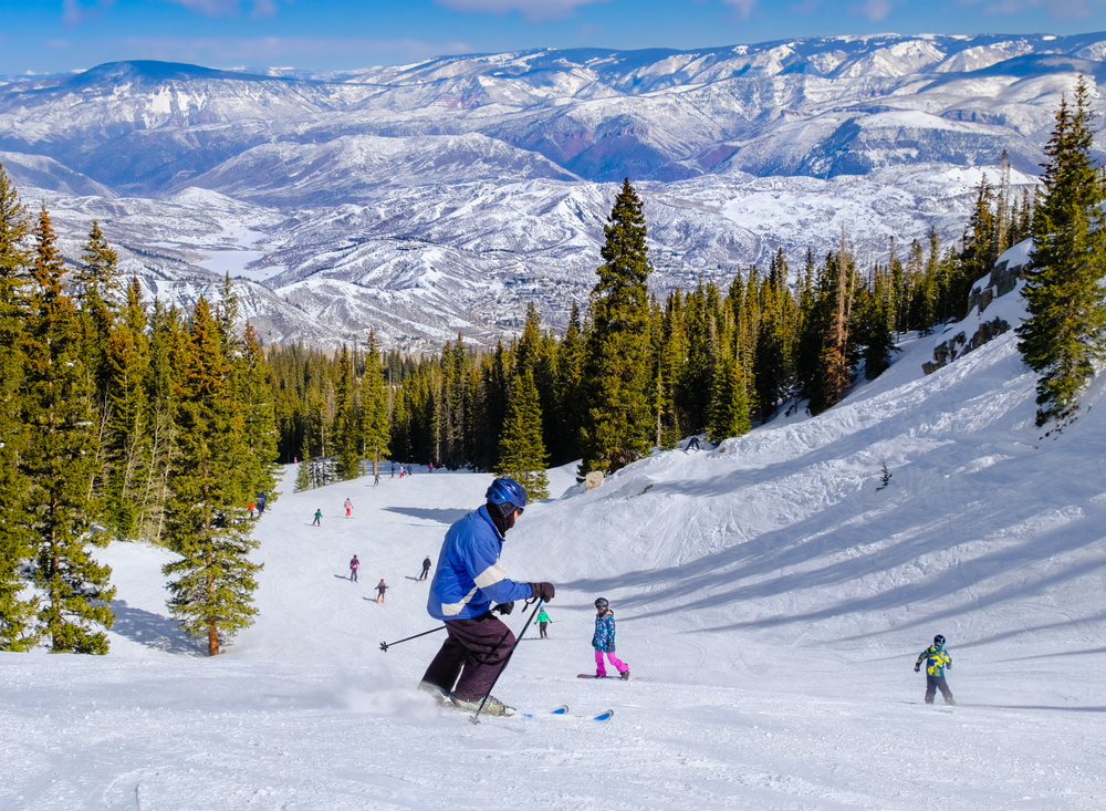 Man in a blue coat skiing down the mountain in Aspen, a top pick for the best ski resorts in Colorado