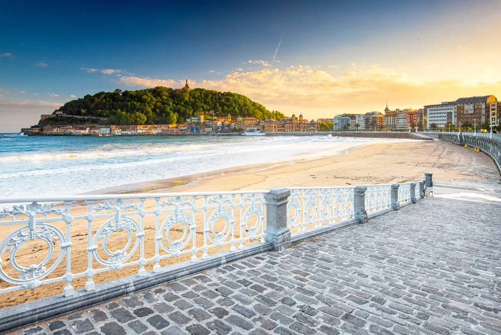 Beach town of San Sebastian pictured with the brick boardwalk along the still water leading to the beach and the city wrapping around the front of the image