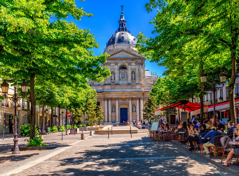 Quartier Latin in Paris pictured with the Sorbonne in the center of the image and a café on the right side