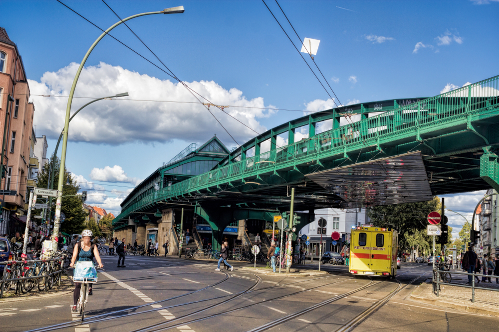 Prenzlauer Berg in Germany, one of the best areas to stay on a trip to Berlin, pictured with a green metal bridge overhead