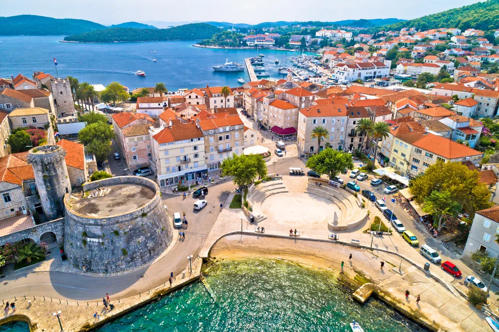For a roundup of the best places to visit in Croatia, an aerial view of the harbor town of Korcula pictured on a sunny day