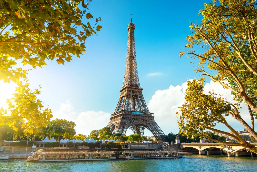 Gorgeous late summer view of the Eiffel Tower pictured towering over the river with a boat motoring down the waterway