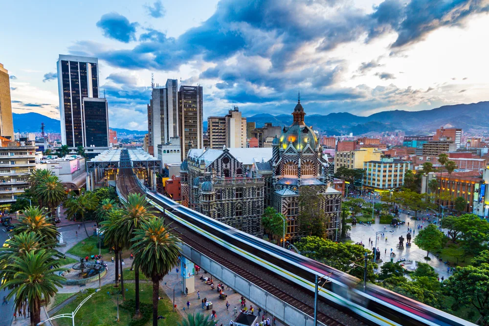 The train tracks in the modern and historic city of Medellin pictured from a high-rise with the sun setting in the distance
