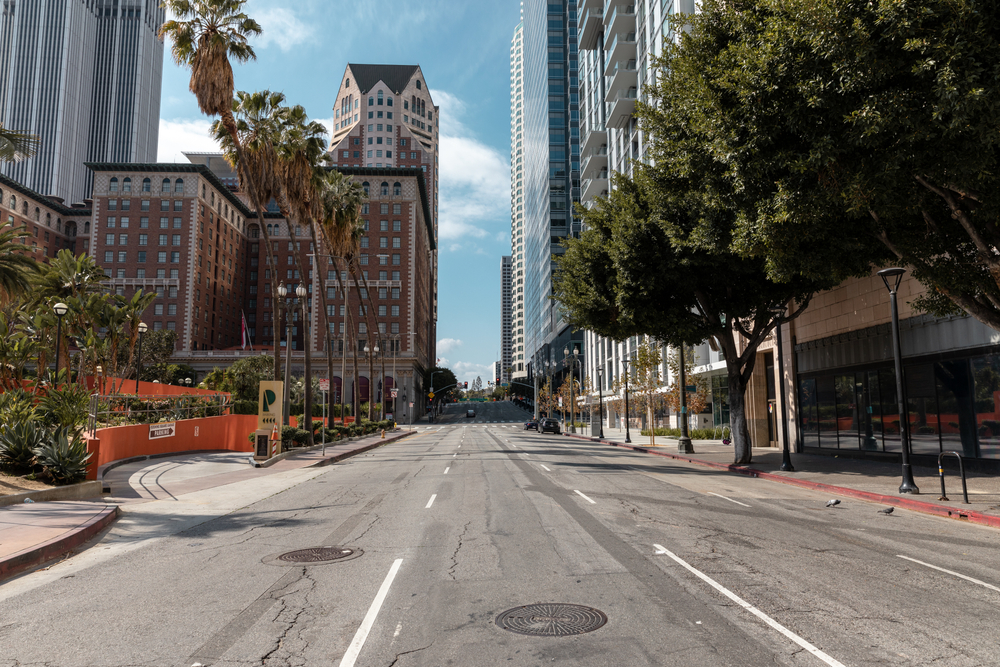 Empty streets of one of Southern California's best places to visit, Los Angeles, pictured with trees on either side