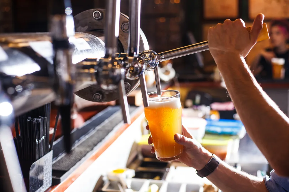 Photo of a bartender pulling a handle to pour a beer into a glass in one of the best places to visit in Delaware, Milton