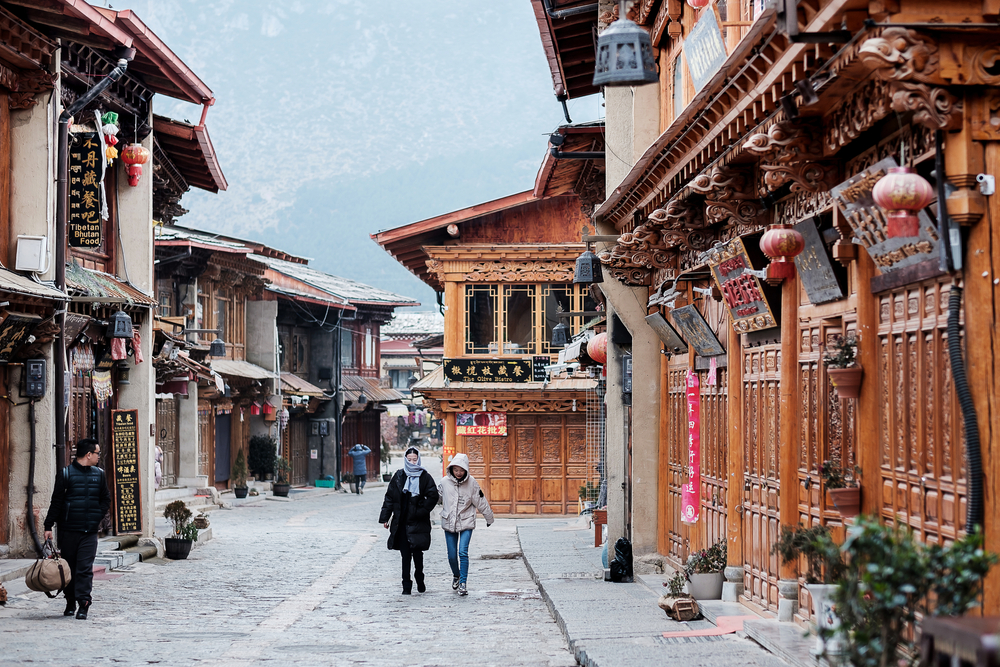 For a piece on the best places to visit in China, pictured is the mystic town of Shangri-La pictured with people walking down the historic streets in the winter