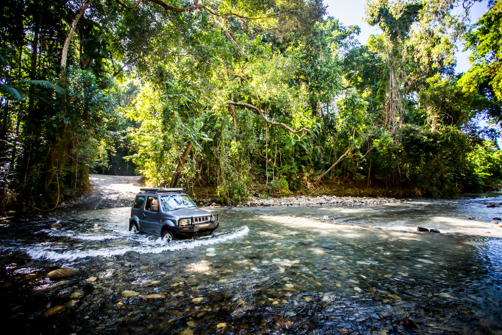 4x4 driving through the Daintree Rainforest with a shallow river flowing under it