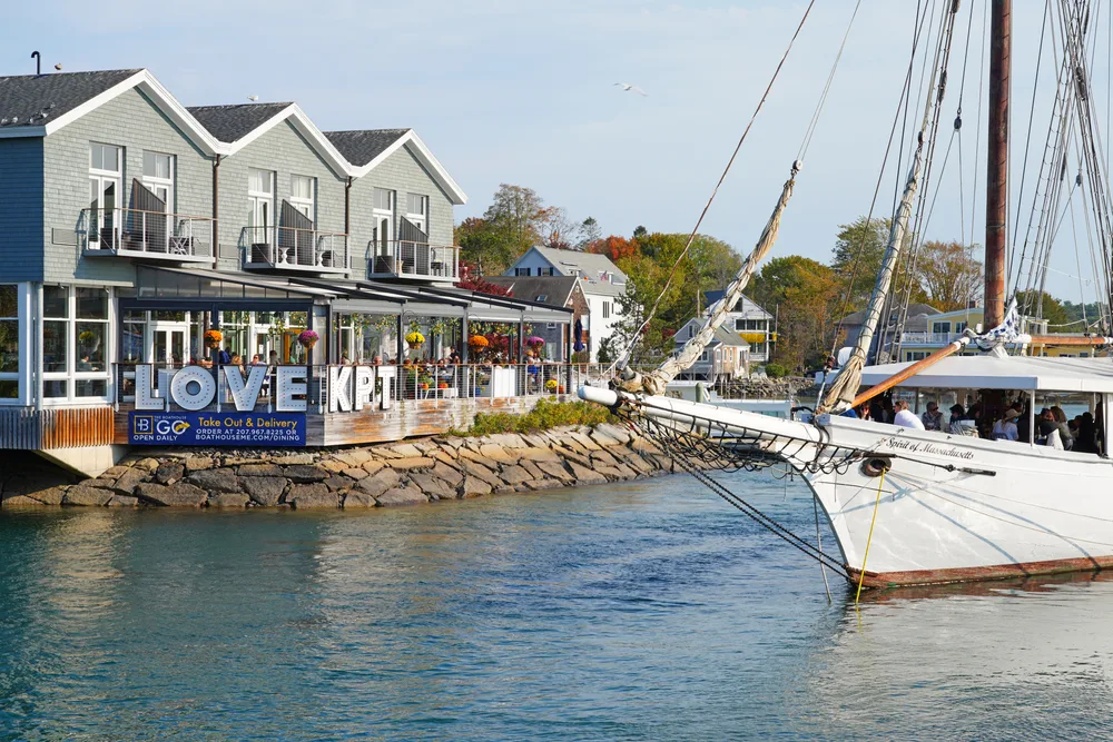 Downtown area with a boat sailing by a restaurant in Kennebunkport, ME