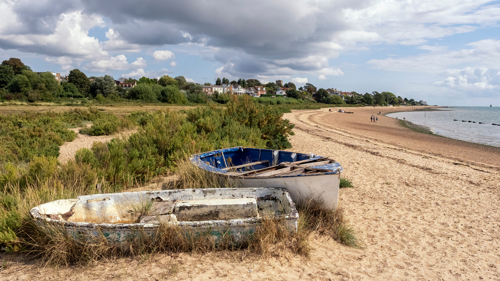 Two little row boats sit on the sand on Mersea Island, one of the best day trips from London