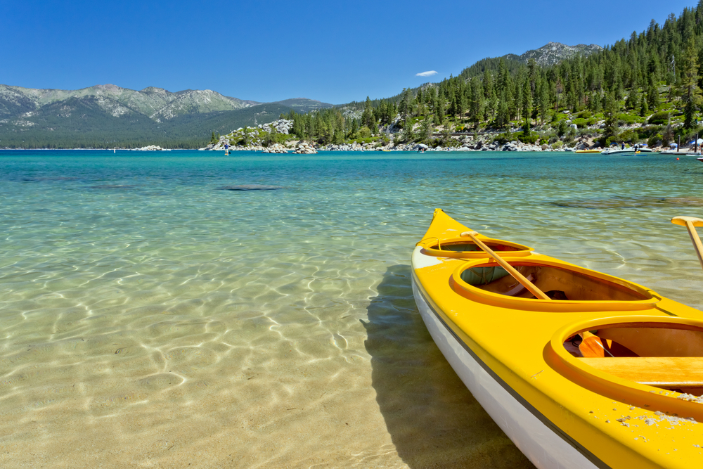 A yellow kayak on the coast of Lake Tahoe, one of the best places to visit in California, with clear water below