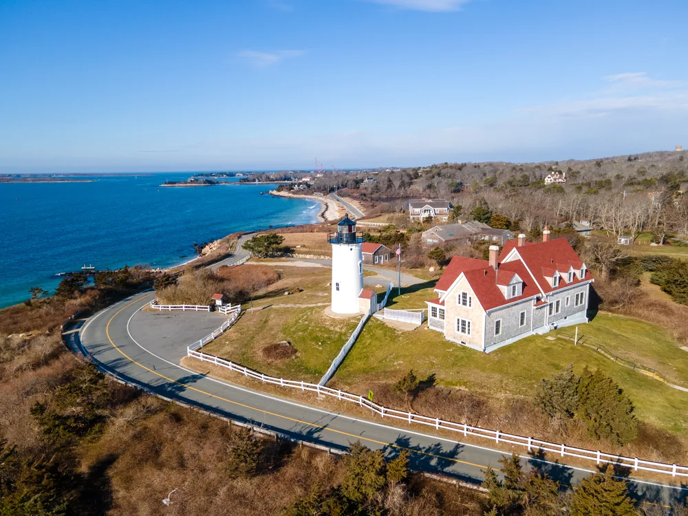 Falmouth lighthouse pictured on the edge of a winding road along the coastline of Cape Cod, one of the best places to take a family vacation
