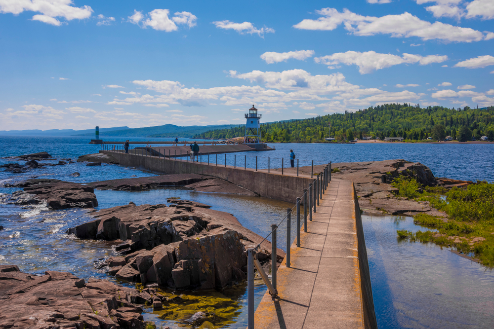 Idyllic and serene zagging walkway going over the rocky water leading to a top pick for the best places to visit in Minnesota, the Grand Marais Lighthouse