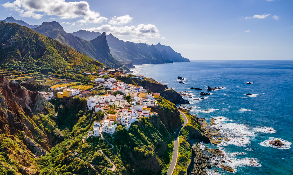 View of the volcanic island of Tenerife, one of the best places to visit in Europe, pictured with a road running just along the coast