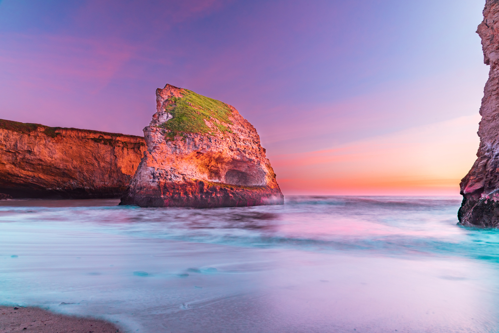 Shark fin cove in Santa Cruz, a top pick for the best day trips from San Francisco, pictured with a pink sky on the horizon