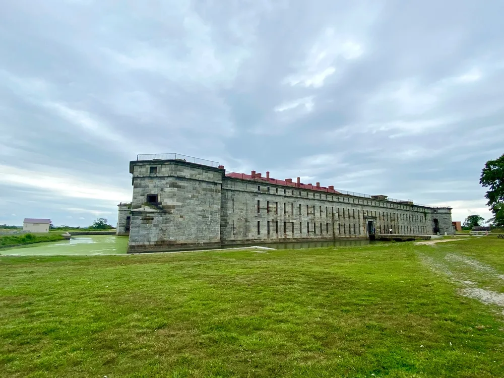 Old stone building in Fort Delaware State Park, one of the best places to visit in Delaware, pictured on a grassy hill