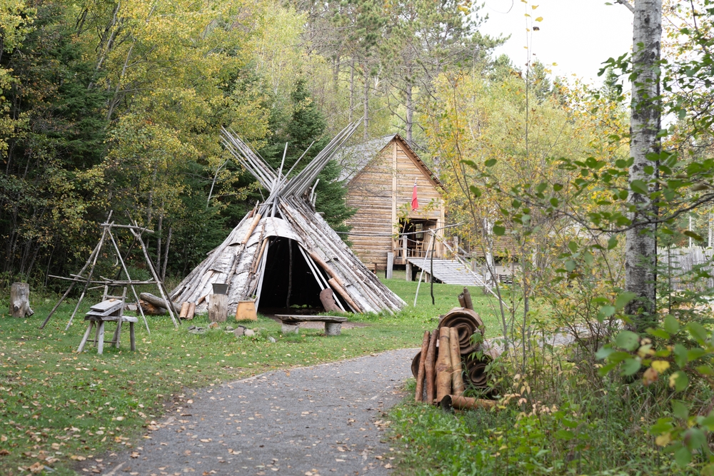 Teepee and old colonial-style house in the middle of a forest, pictured for a piece on the best places to visit in Minnesota