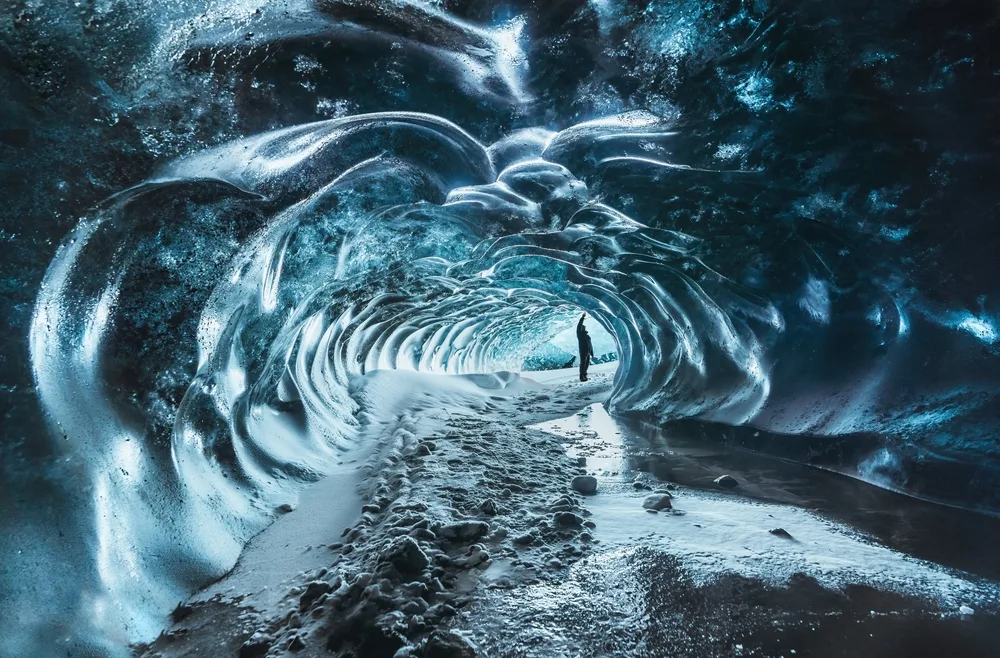 Man walking through ice caves in Skaftafell National Park, one of the must-visit places in Iceland, that almost look like they're fake or from another world