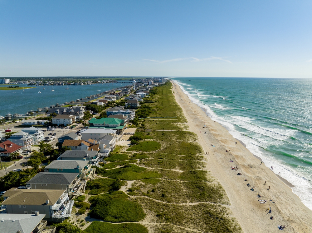 Aerial image of the beachfront homes in one of North Carolina's best places to visit, the Outer Banks, pictured on a summer day