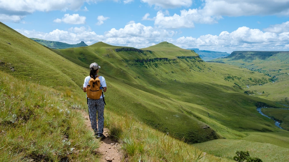 Young Asian woman hiking through the Drakensburg mountain region, a top picks for must-visit places in South Africa