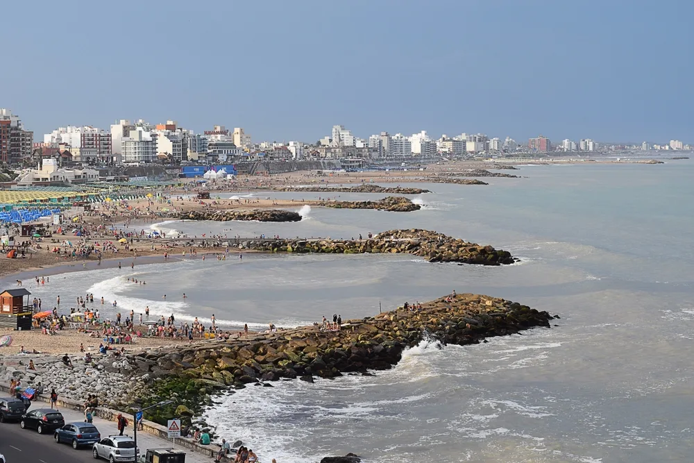 Featured as one of the best places to visit in Argentina, the idyllic stone jetties at Mar del Plata are seem from a drone looking down the coastline