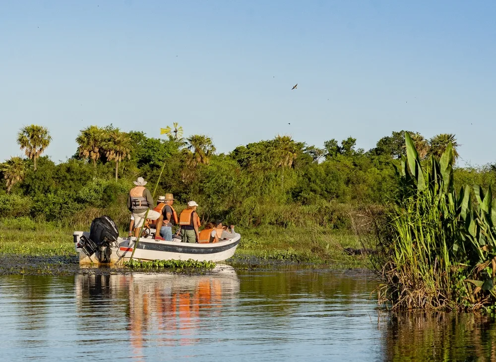Several people in orange lifejackets making their way through the Ibera Wetlands, one of the best places to visit in Argentina