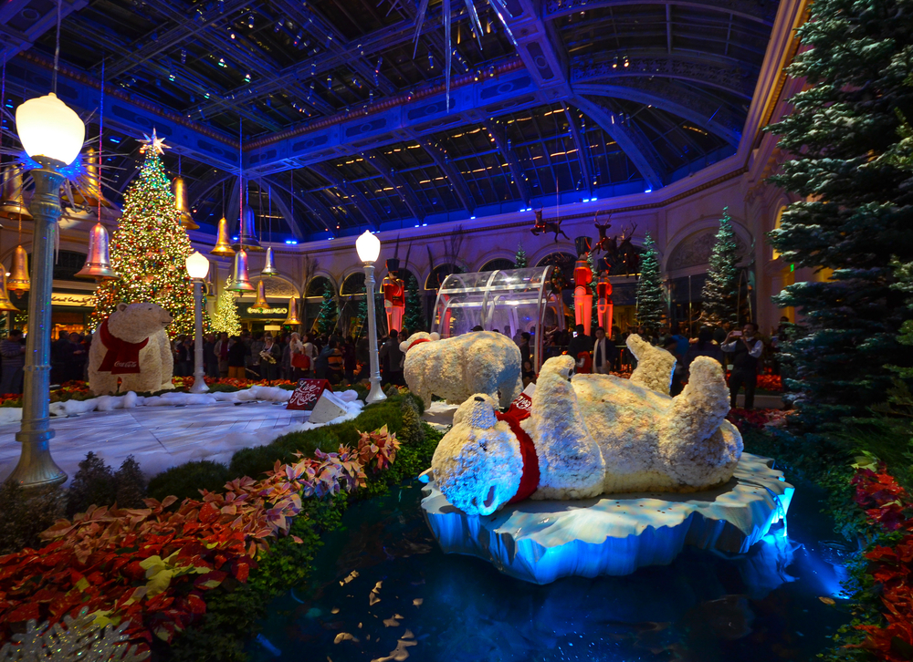 For a roundup of the best places to visit during Christmas in the USA, a bear lies on his back next to other Christmas decorations in the Bellagio