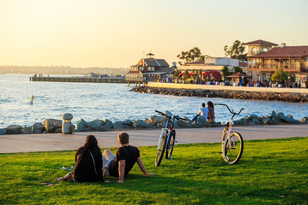 Attractive couple sitting on the grass next to bicycles pictured in San Diego, one of the best places to visit in California