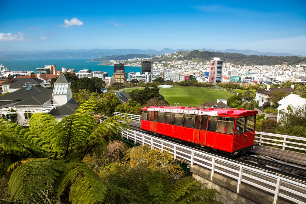 Red cable car making its way up the track and overlooking the gorgeous coastal city below