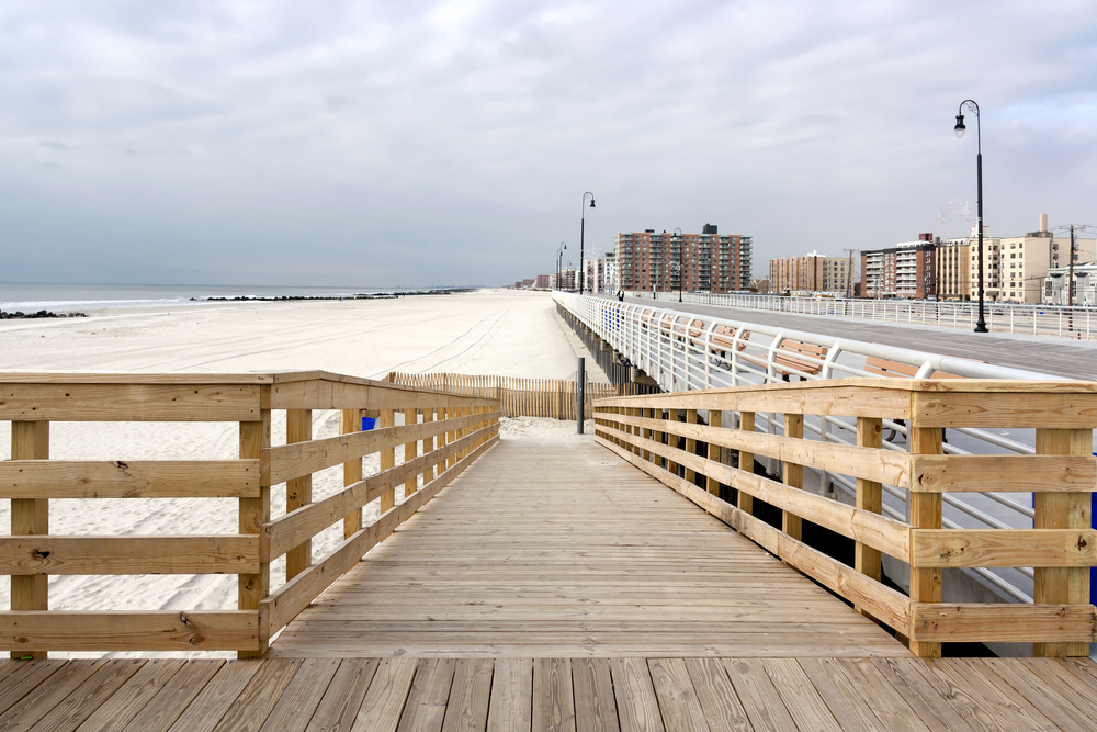 Boardwalk in Long Beach, New York, with white sand and clouds overhead