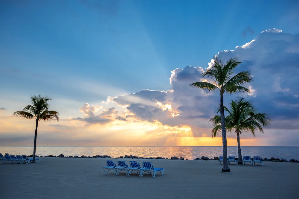Key Largo sunset on the beach with chairs lined up and palm trees for a frequently asked questions section on the islands in the Keys you should visit