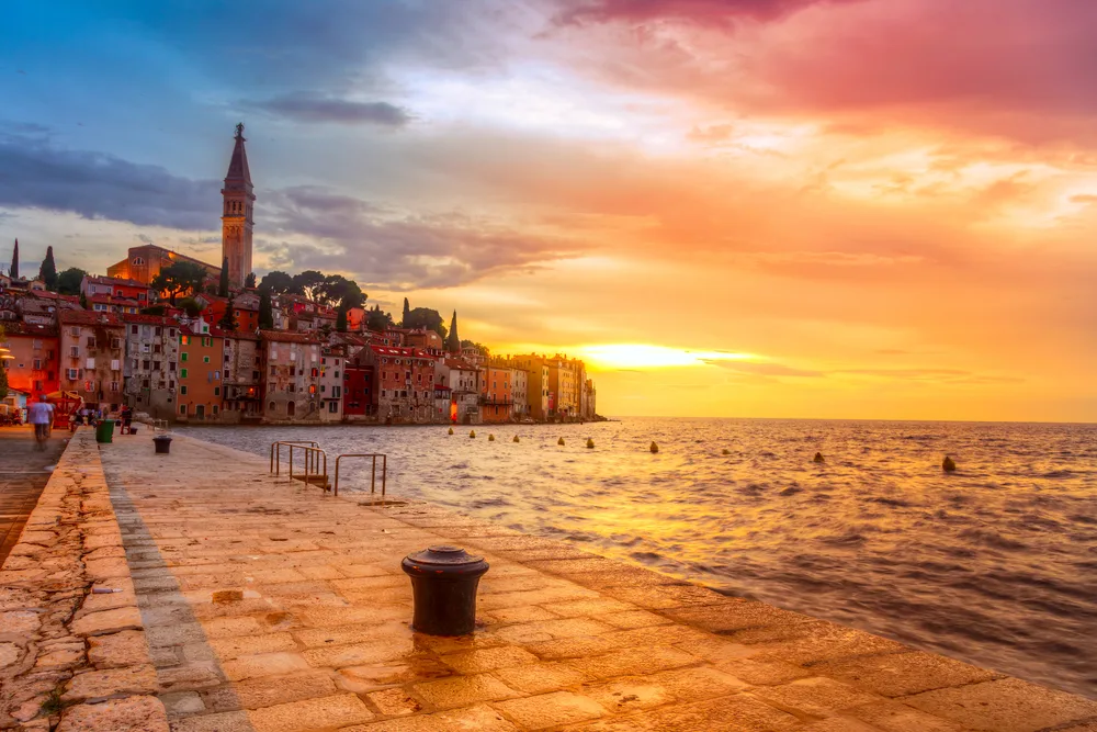 Idyllic view of the sun setting over the stone pier at Rovinj, one of our top picks for must-see places in Croatia