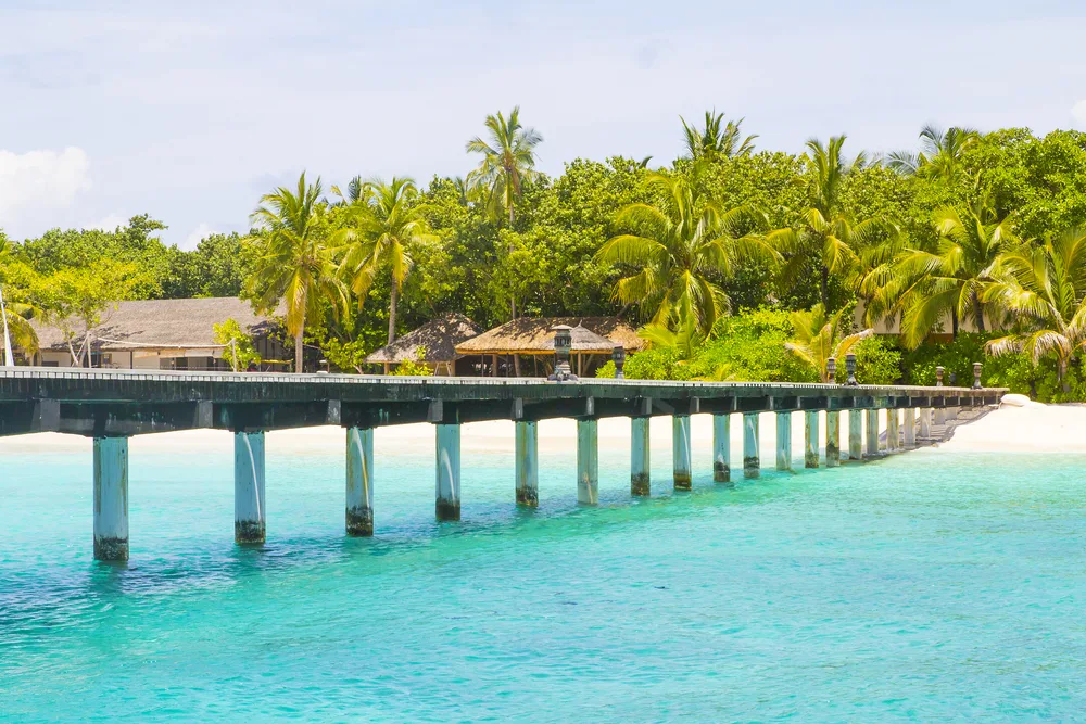Fonimagoodhoo Island shown as the #4 best island in the Maldives with a pier and green trees in the background over blue water