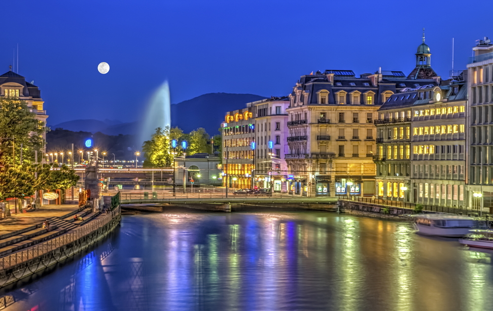 Night view of the famous fountain with a full moon in the sky in Geneva, one of the best places to visit in Switzerland