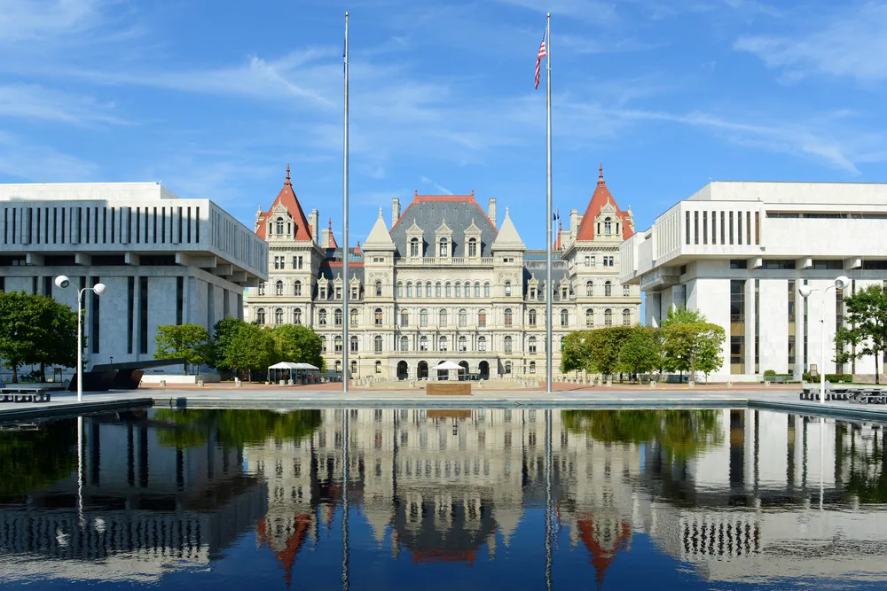 New York State Capitol Building pictured reflecting into a still water pond in front of it