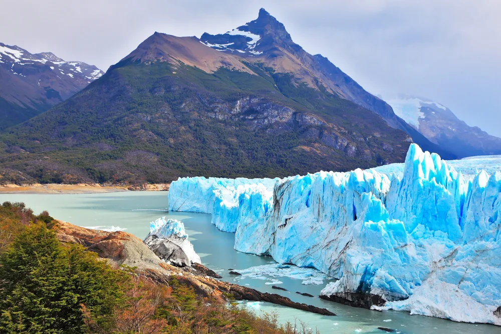 Giant ice formations on the water next to a giant volcanic mountain in Los Glaciers National Park, one of the best places to visit in Argentina