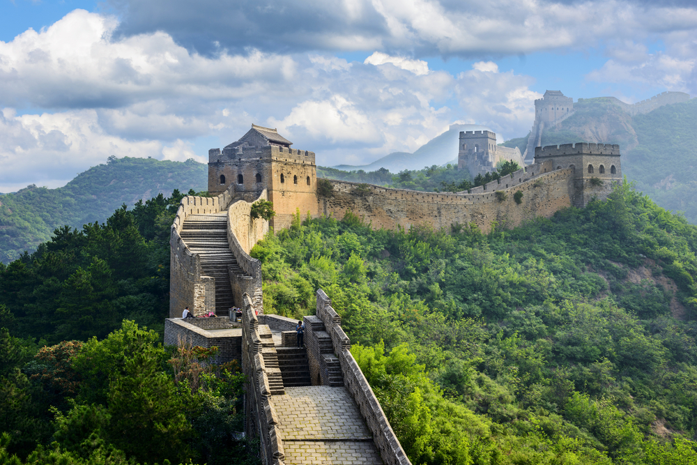 Great Wall of China pictured snaking up the lush green hillside with various observation towers along the route