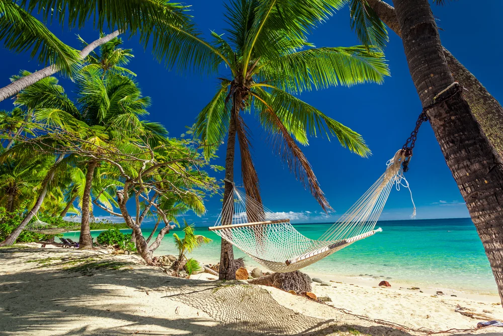 Hammock slung between two trees pictured just outside one of the best over-water bungalows in Fiji