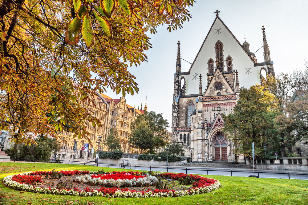Front of the St. Thomas church in Leipzig, one of the best places to visit in Germany, as seen on a nice day from behind the flowers in front of the church