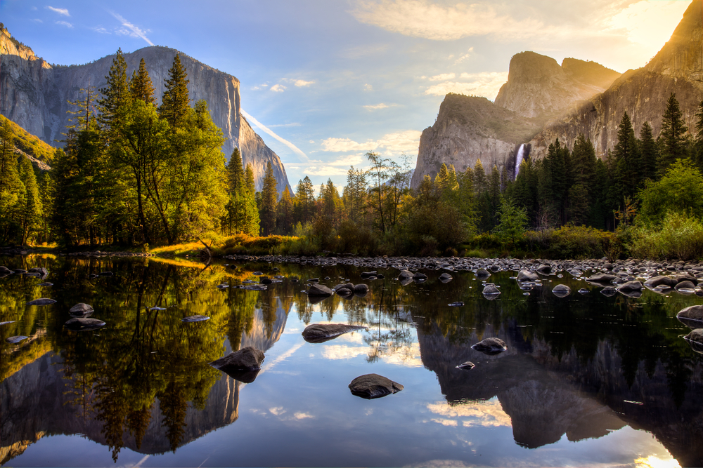 Sunrise over El Cap in Yosemite, with still water and gorgeous trees all around, pictured for a piece on the best family vacation spots