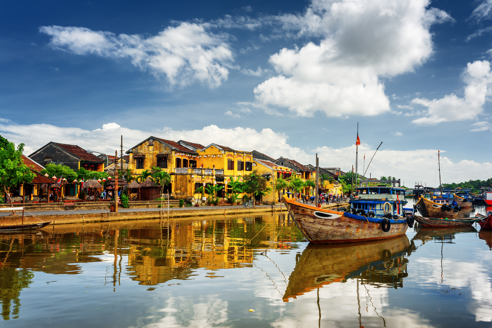 For a roundup on the best places to visit in Asia, a few wooden boats floating on the water outside of the small town of Hoi An