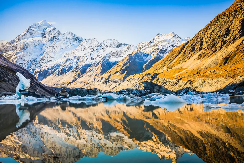 Snow-capped Aoraki, aka Mount Cook, pictured towering over the valley below with a lake in the middle of the mountain range