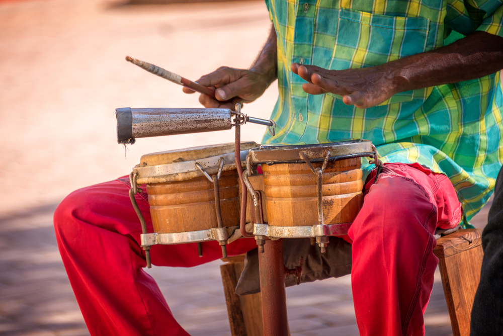 Street musician playing bongo drums in Trinidad wearing colorful Caribbean clothes for a piece on the best islands in the Caribbean