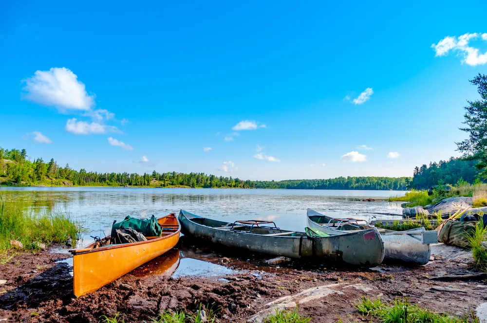 Three metal canoes on the Boundary Waters, a must-visit place in Minnesota, moored on the rocky coastline of the lake
