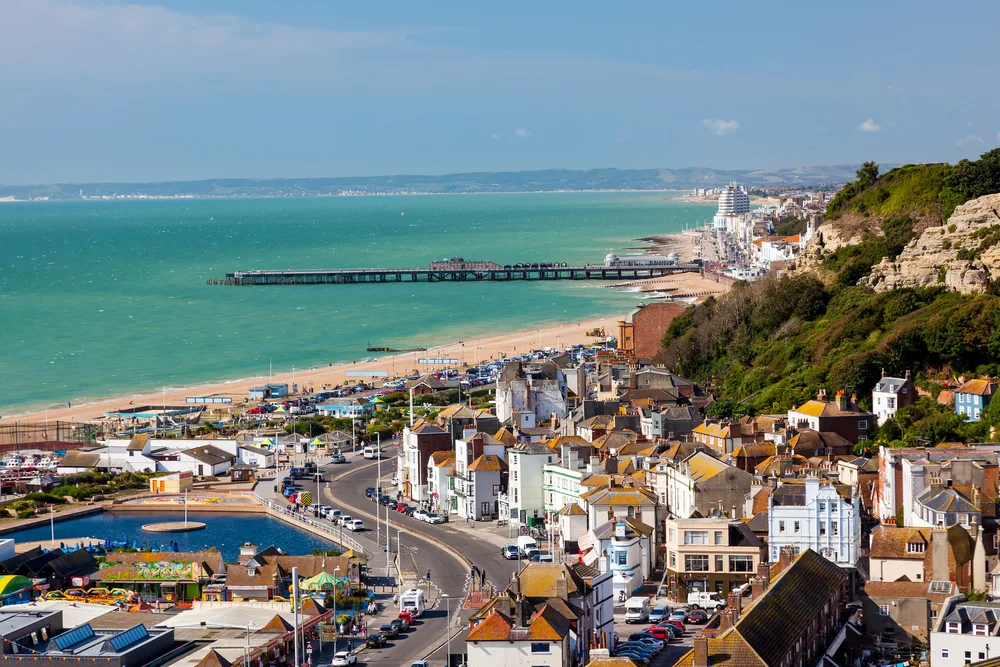 Old pirate town of Hastings, England, seen with its teal water below the winding streets and cliffside buildings and homes