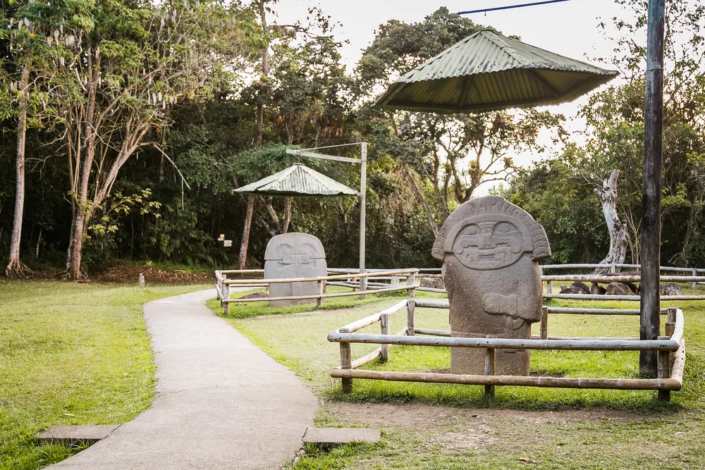 Photo of the smiling rock idol statues by the walking path in the San Augustin Parque